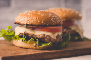 two burgers on a cutting board 