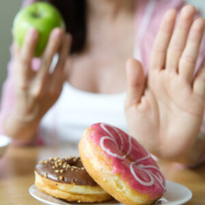woman choosing an apple over donuts