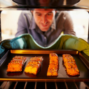 man placing salmon filets in the oven